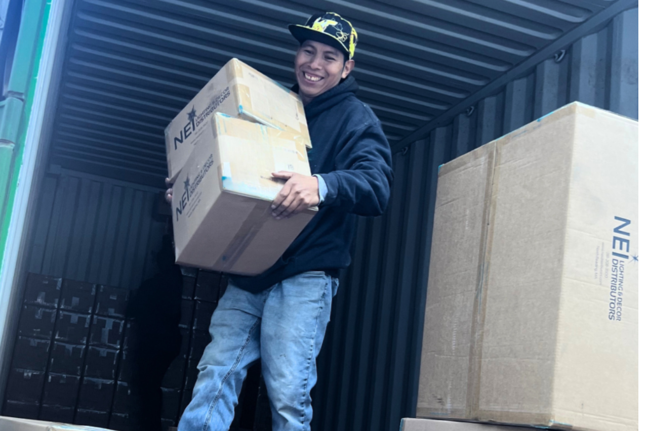 NEI Distributors large brown shipping container boxes with smiling worker North Reading MA.
