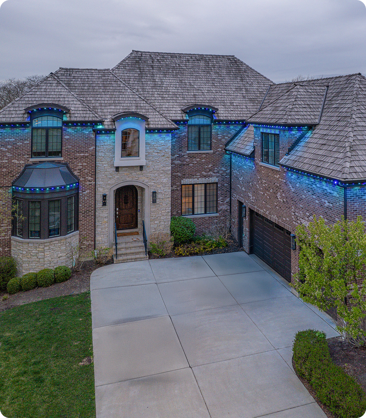 Two story brick house blue white roofline lighting large driveway NEI Distributors North Reading MA.