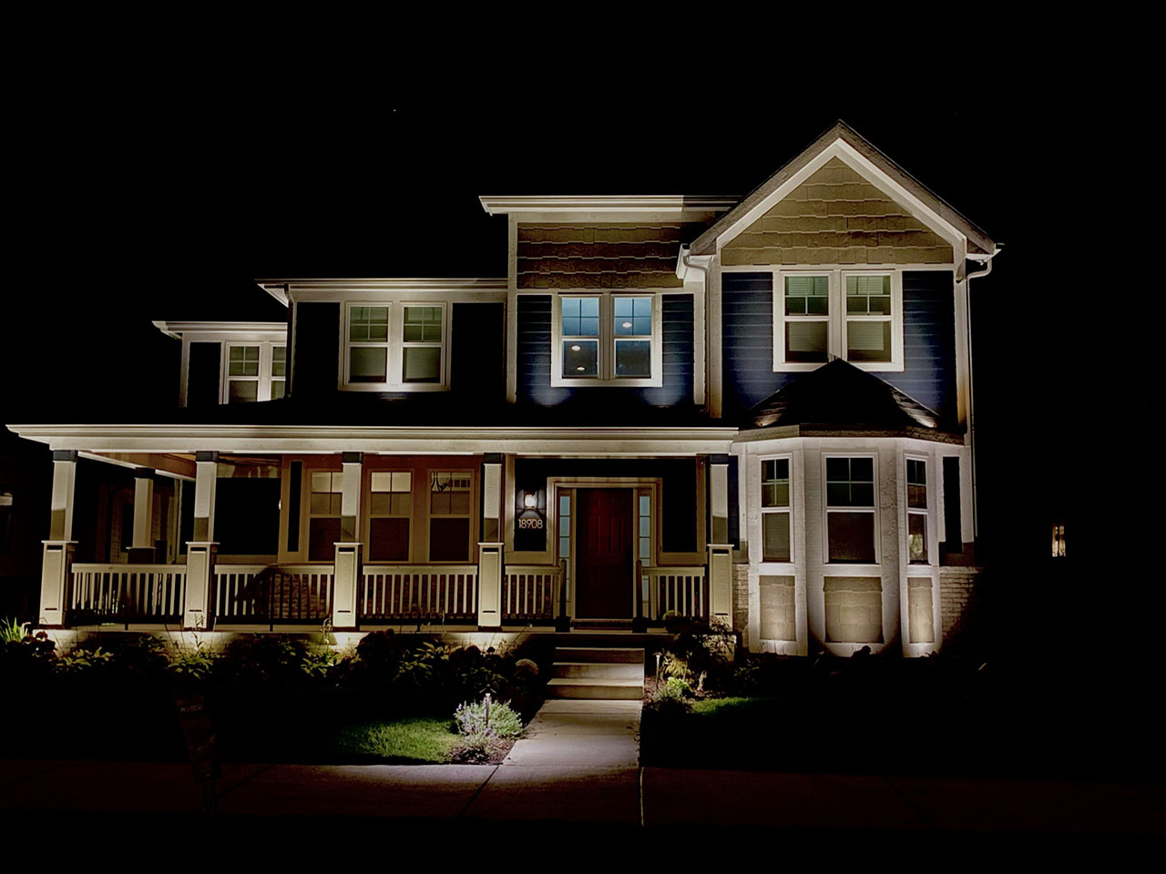 Two story beige house with porch and landscape lights large windows NEI Distributors North Reading MA.