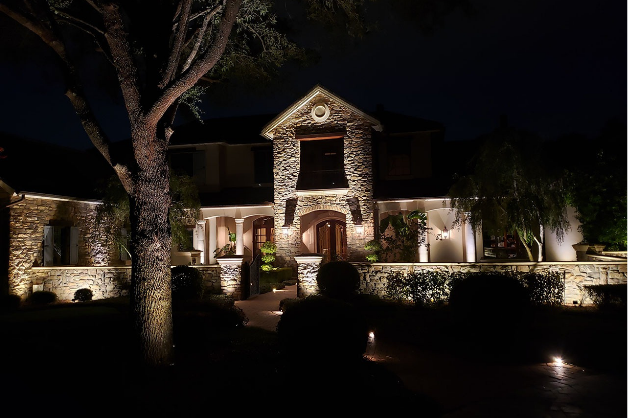 Stone house large illuminated warm lighting textured facade dark sky NEI Distributors North Reading MA.